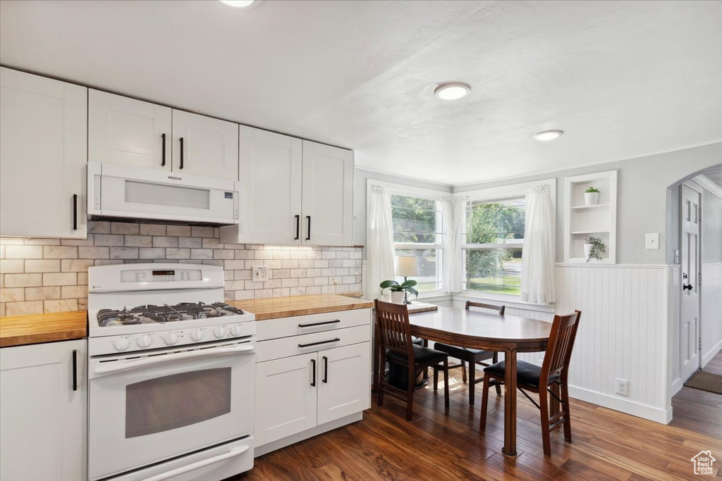 Kitchen with white appliances, wood counters, arched walkways, white cabinetry, and dark wood finished floors