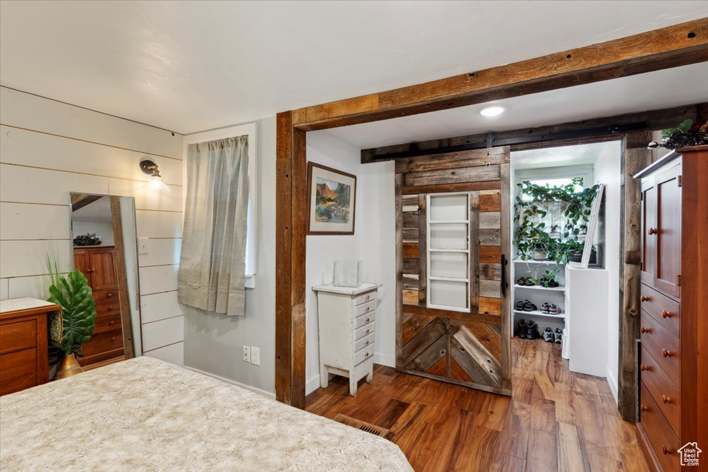 Bedroom with wood finished floors, wooden walls, and beam ceiling