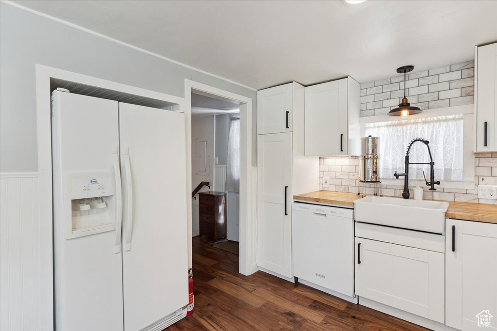 Kitchen featuring white appliances, butcher block counters, backsplash, white cabinets, and pendant lighting