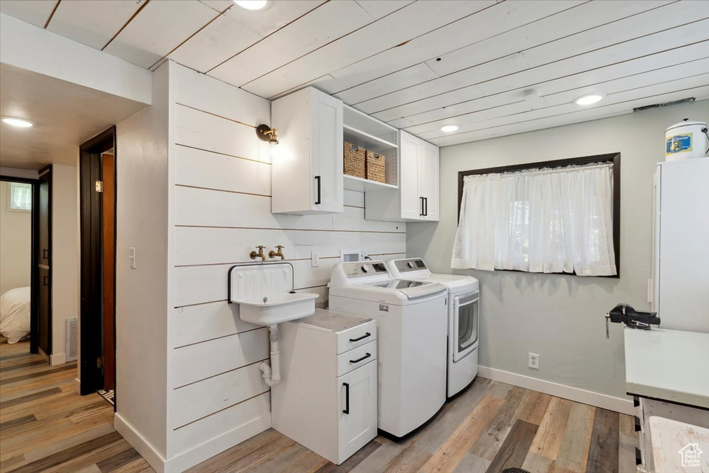 Washroom with washing machine and dryer, light wood-style floors, and recessed lighting