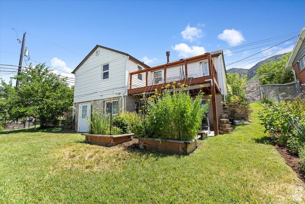 Back of property with a wooden deck and a vegetable garden