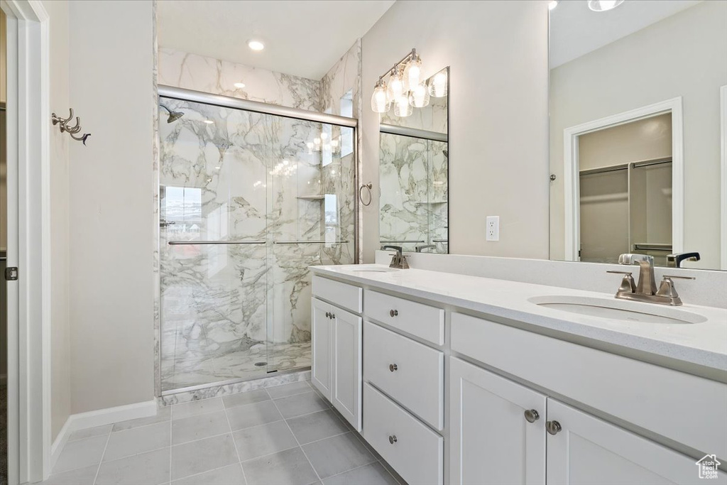 Full bathroom with a marble finish shower, a walk in closet, double vanity, and tile patterned flooring