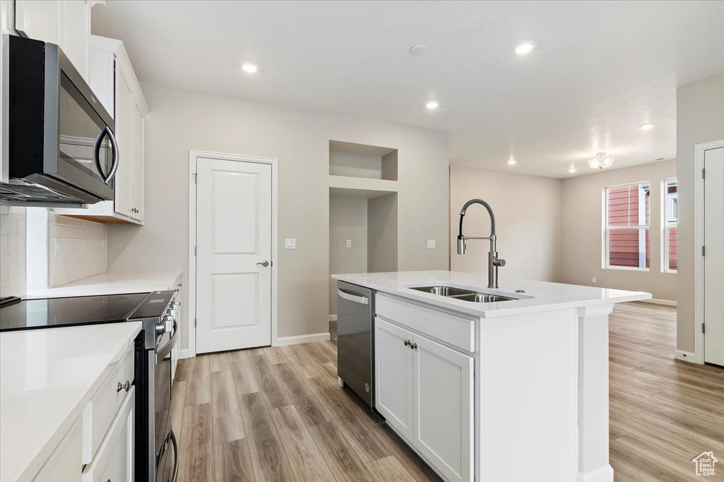 Kitchen featuring appliances with stainless steel finishes, light wood-style floors, white cabinets, and recessed lighting