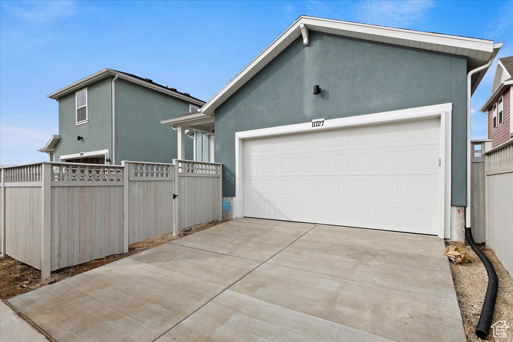 View of side of home with stucco siding, driveway, and a garage
