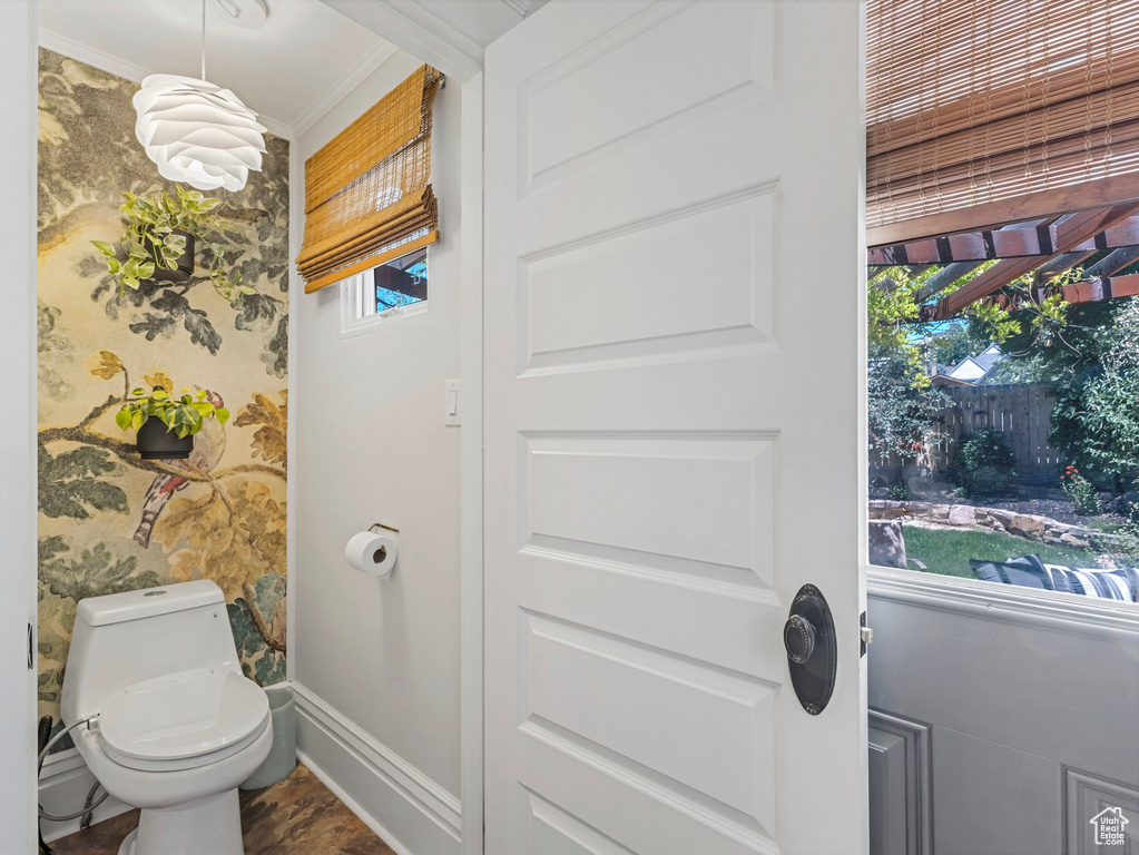 Bathroom with ornamental molding and wallpapered walls