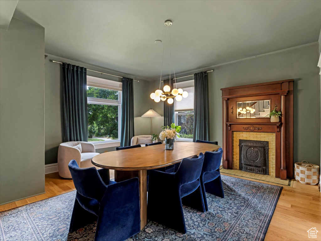 Dining space with a tiled fireplace, light wood-style flooring, and a chandelier