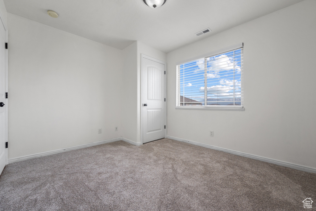 Carpeted empty room featuring a smoke detector and baseboards