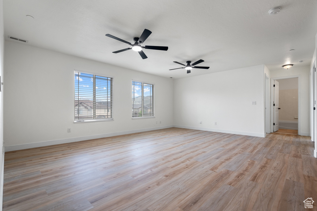 Empty room with ceiling fan and light wood finished floors