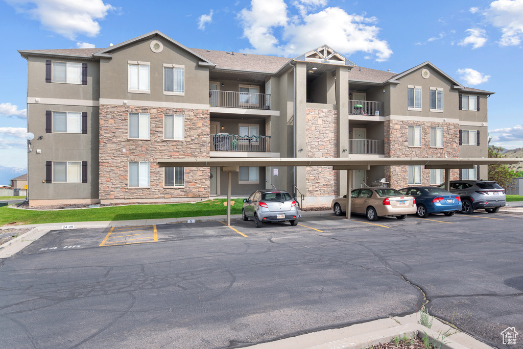 View of apartment building / complex with covered and uncovered parking