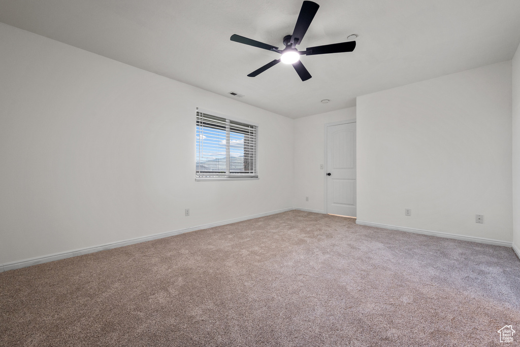 Carpeted spare room featuring a ceiling fan and baseboards