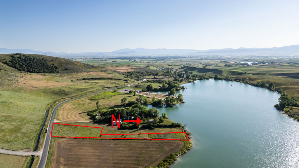 Aerial view of property and surrounding area featuring property parcel outlined and a water and mountain view