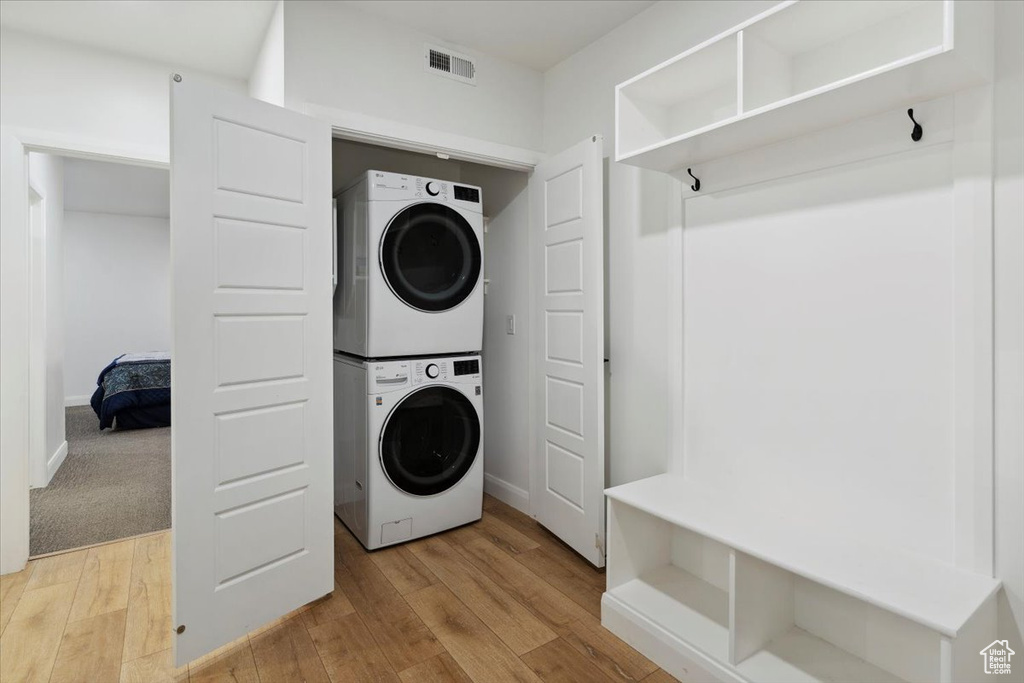 Laundry room with estacked washer and dryer and light wood finished floors