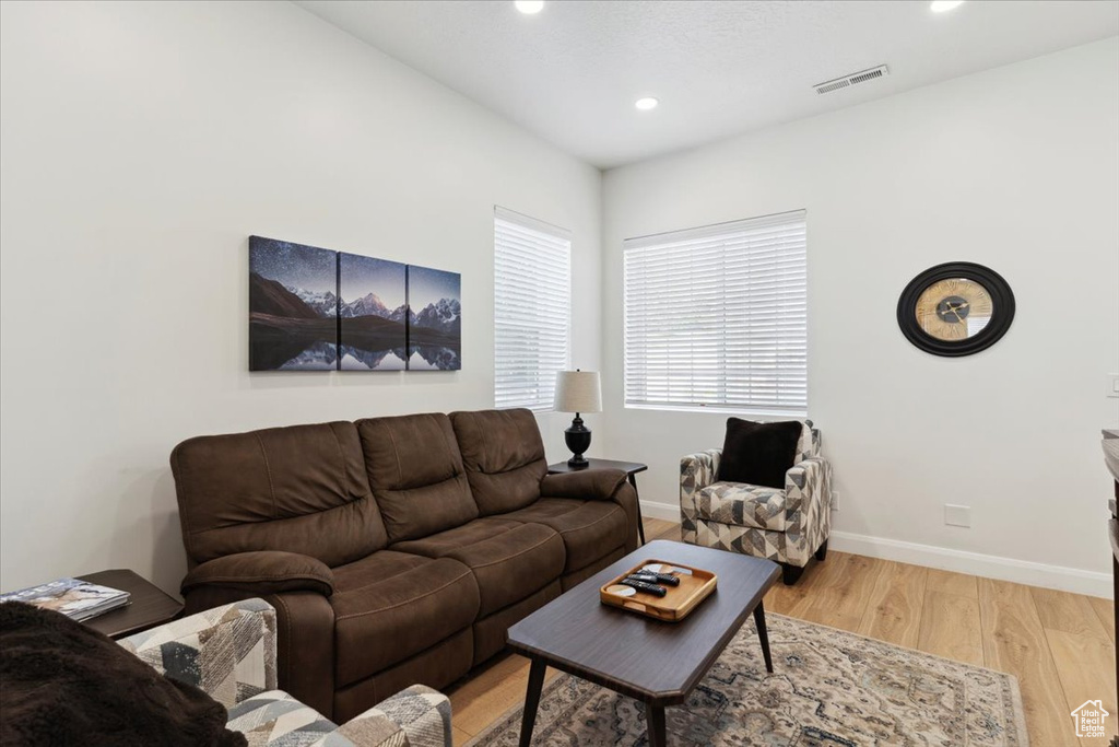 Living area with light wood-type flooring and recessed lighting