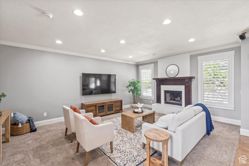 Living room with crown molding, recessed lighting, and a fireplace with raised hearth