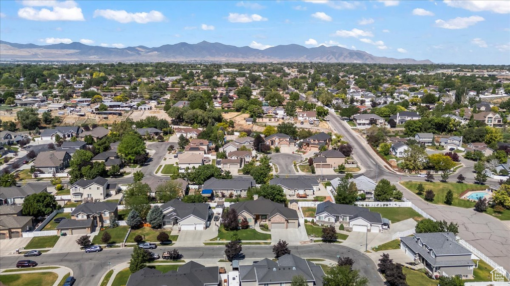 Aerial view of property and surrounding area featuring a mountain backdrop and nearby suburban area
