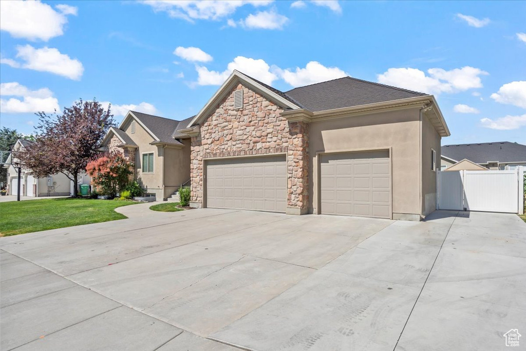 View of front of home with concrete driveway, a garage, stone siding, and stucco siding