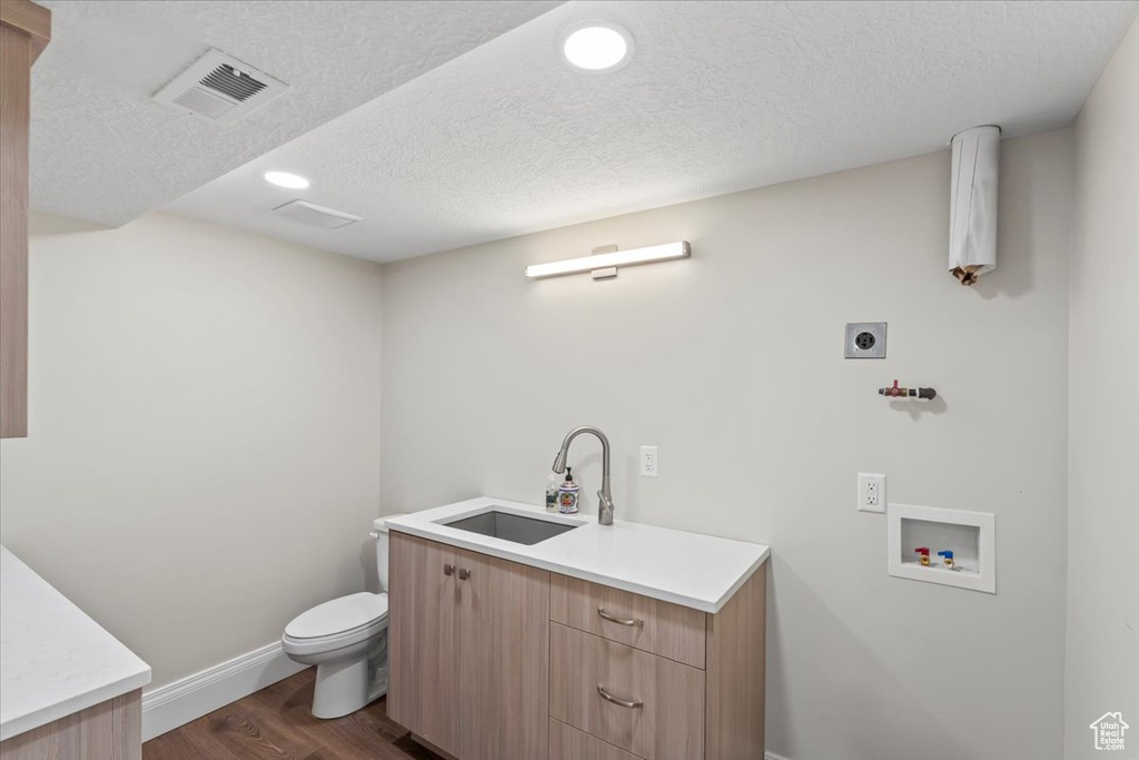 Washroom featuring hookup for an electric dryer, dark wood-style floors, hookup for a washing machine, a textured ceiling, and recessed lighting