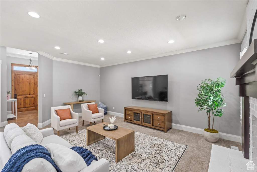 Living area with recessed lighting, a fireplace, ornamental molding, and light colored carpet