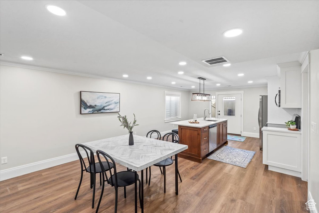 Dining area with recessed lighting, ornamental molding, and light wood-style floors