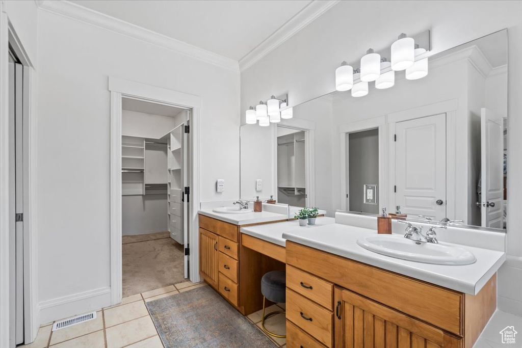 Full bath featuring double vanity, a spacious closet, crown molding, and tile patterned floors