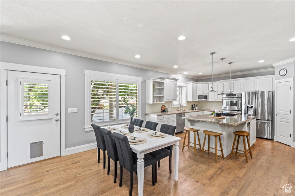 Dining area with ornamental molding, plenty of natural light, recessed lighting, and light wood finished floors