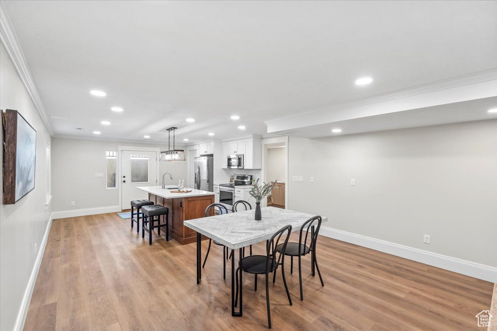 Dining area with ornamental molding, recessed lighting, and light wood-style flooring