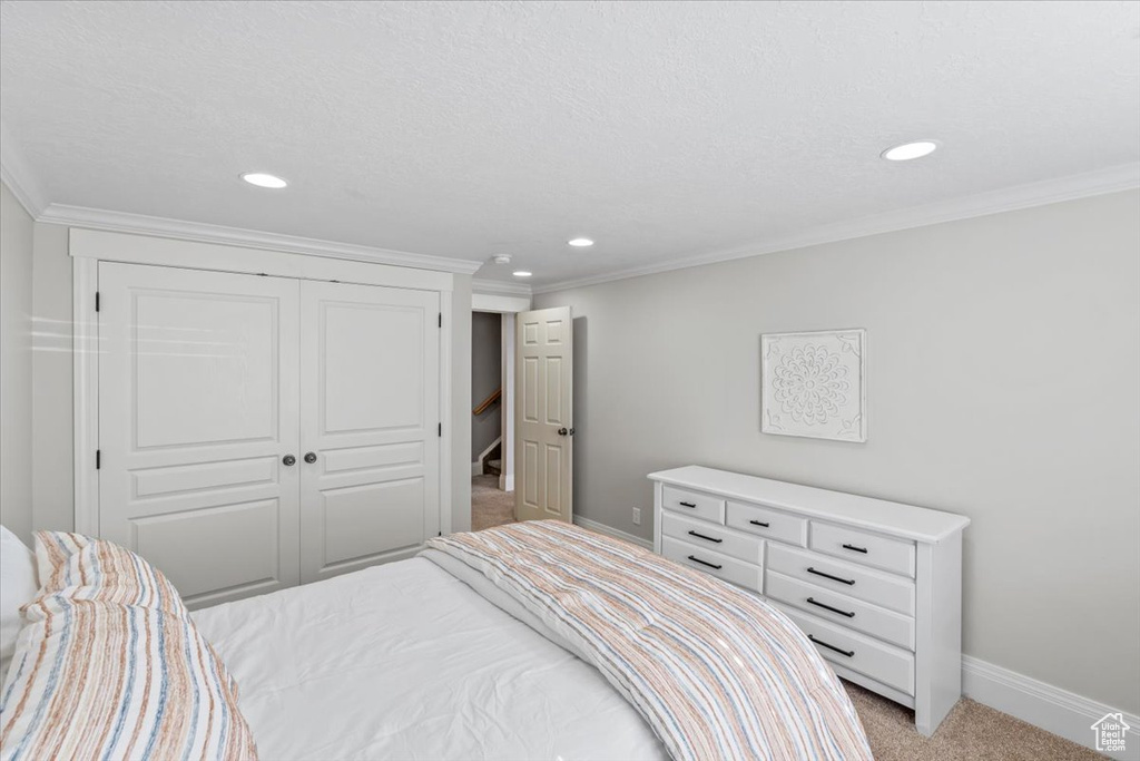 Bedroom with light colored carpet, recessed lighting, a closet, and ornamental molding