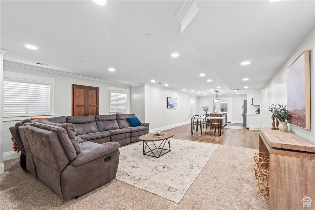 Living room with recessed lighting, ornamental molding, and light wood-style floors