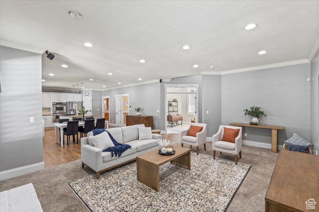 Living area with recessed lighting, light carpet, and ornamental molding