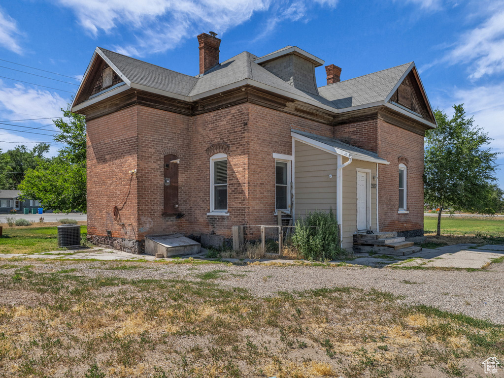 View of side of property featuring a chimney and brick siding