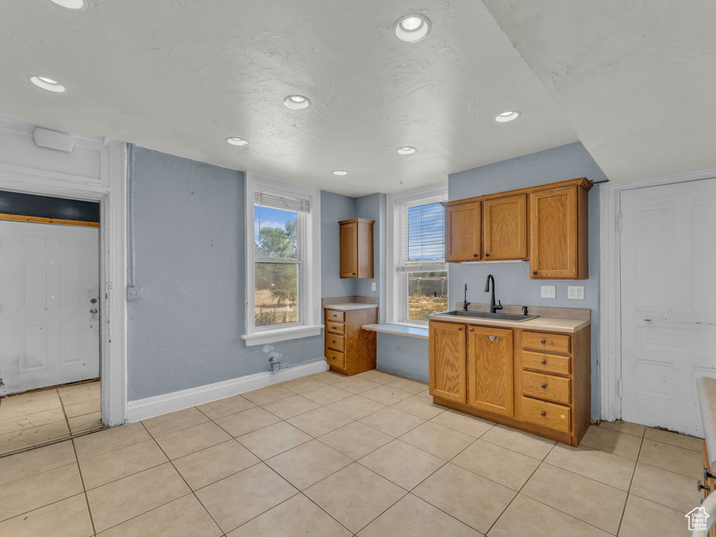 Kitchen with light countertops, brown cabinetry, light tile patterned floors, and recessed lighting