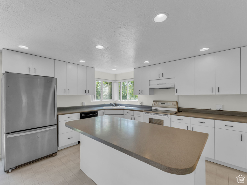 Kitchen featuring freestanding refrigerator, white electric range oven, under cabinet range hood, dark countertops, and recessed lighting