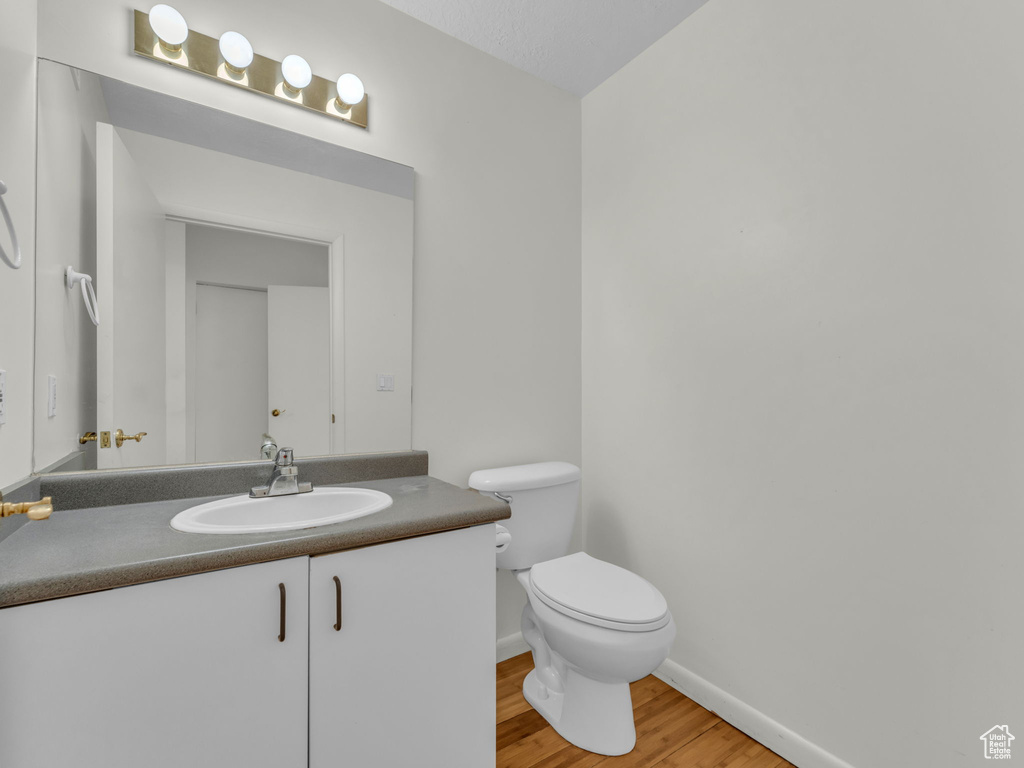 Half bath with wood finished floors and vanity