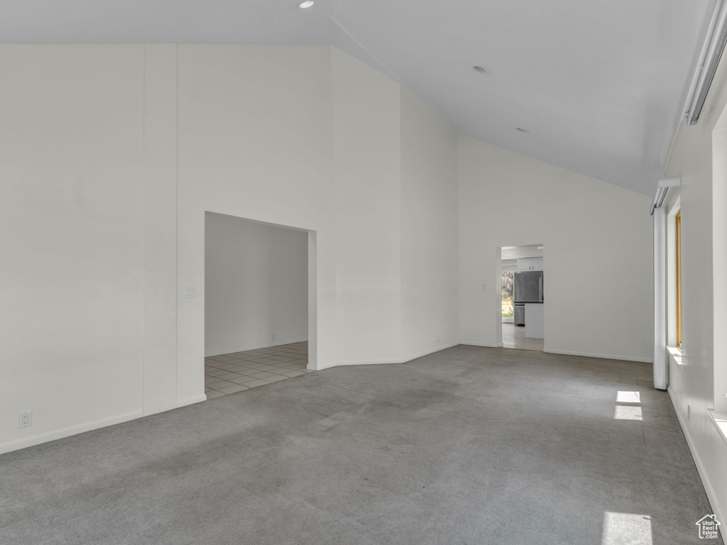 Carpeted spare room featuring high vaulted ceiling