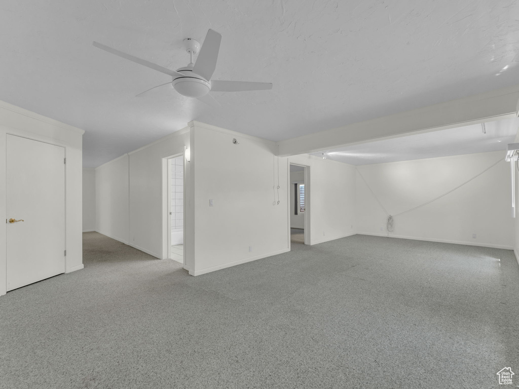 Carpeted spare room with a ceiling fan and baseboards