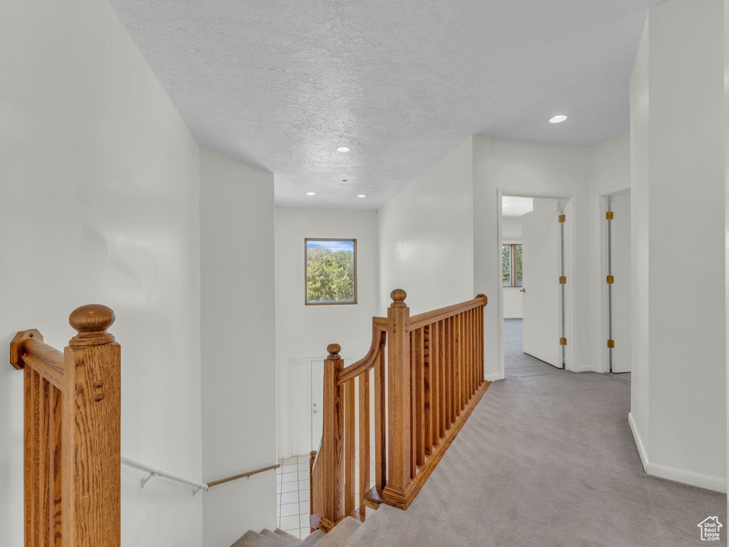 Corridor featuring an upstairs landing, a textured ceiling, carpet, and recessed lighting