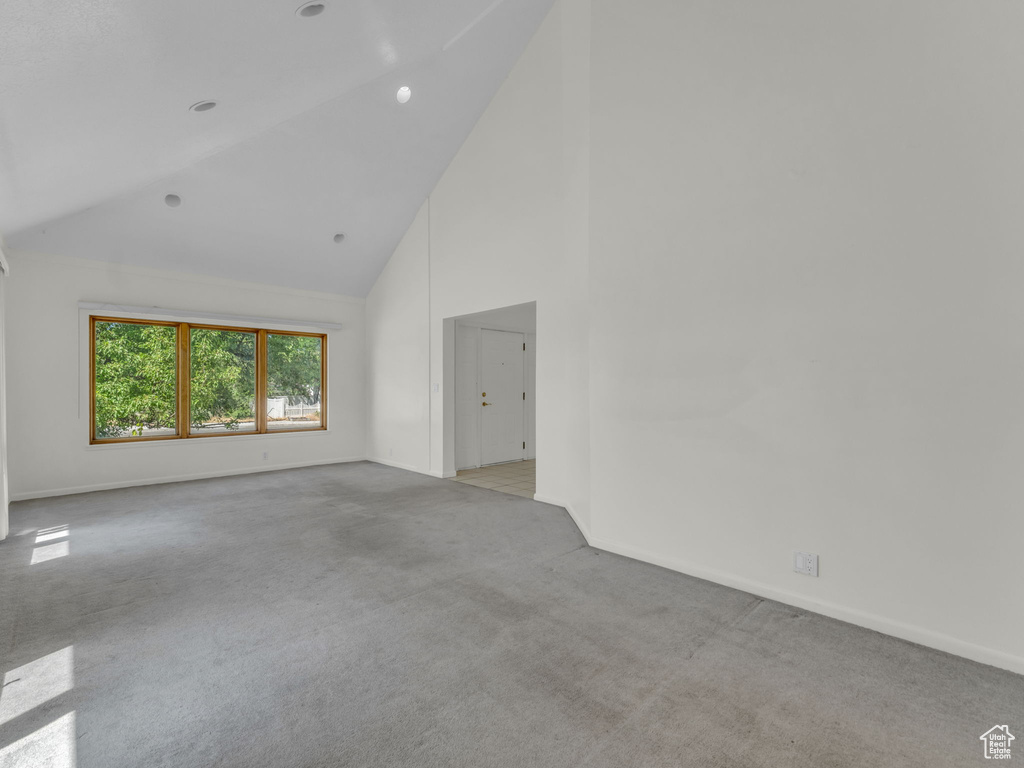 Spare room featuring high vaulted ceiling and light carpet