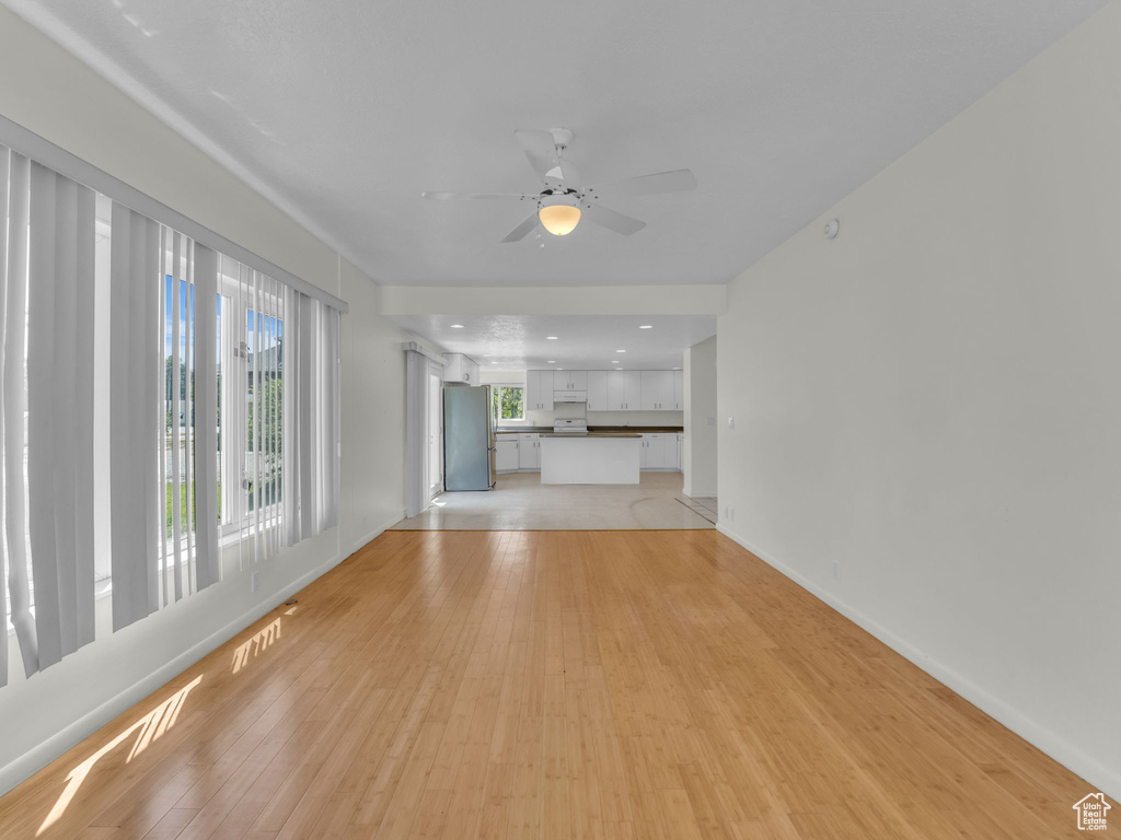 Unfurnished living room featuring light wood-style floors and ceiling fan