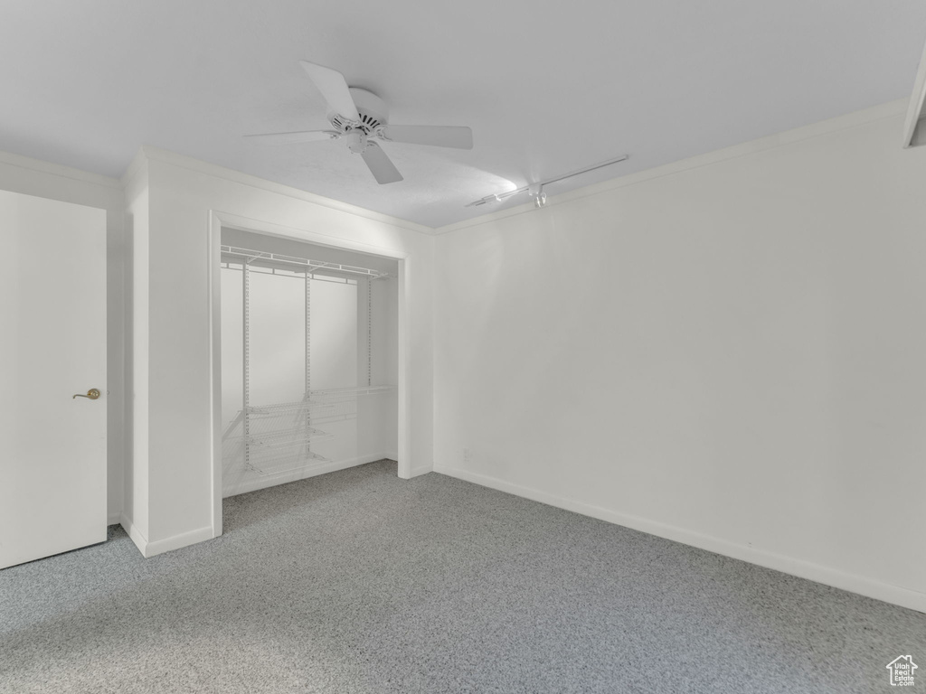 Unfurnished bedroom featuring carpet flooring, crown molding, attic access, ceiling fan, and a closet