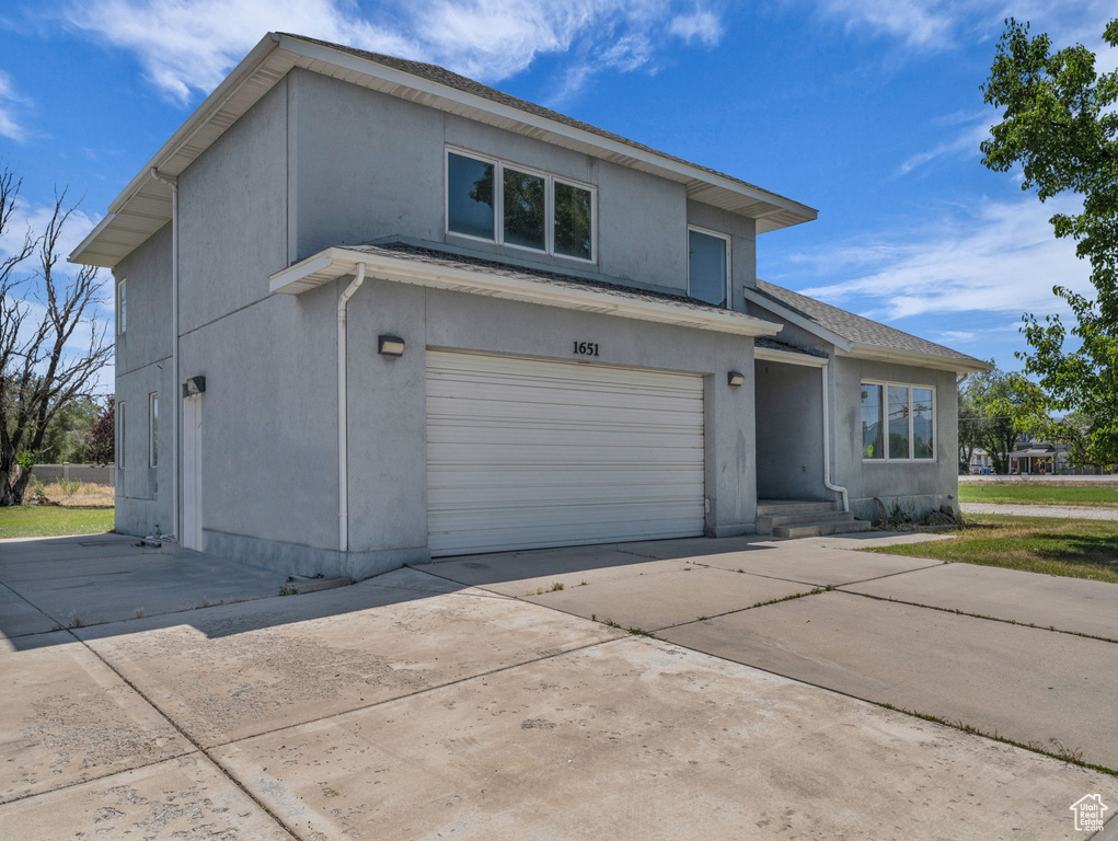 Traditional-style home with stucco siding, a garage, and driveway
