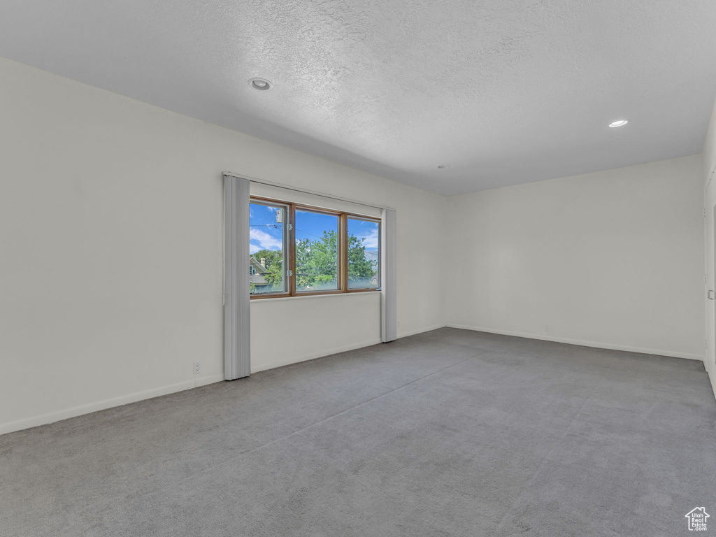 Carpeted spare room featuring a textured ceiling and recessed lighting