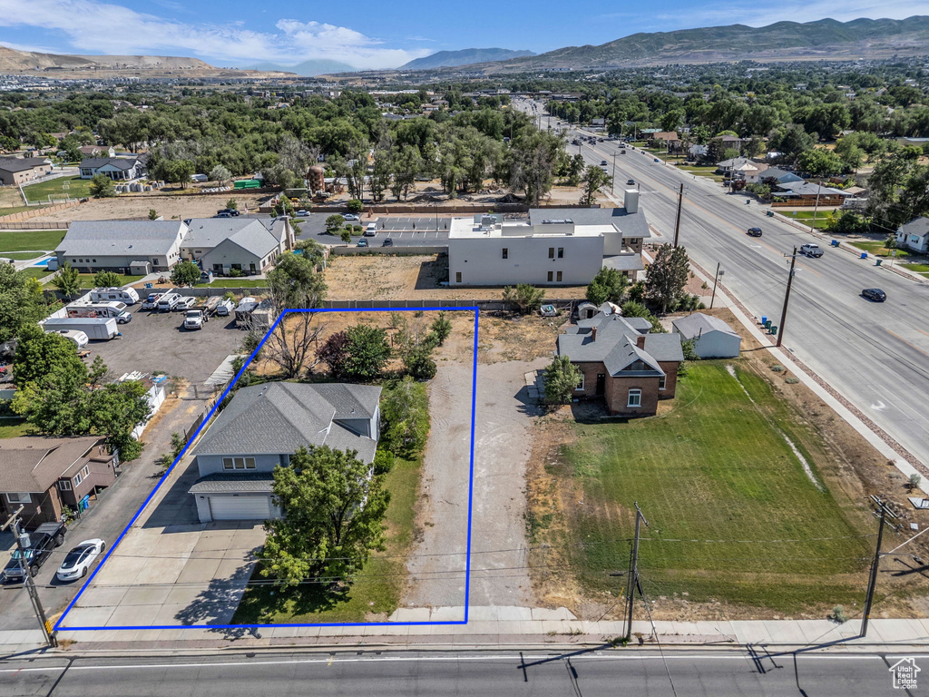 Aerial view of residential area with property parcel outlined and a mountainous background