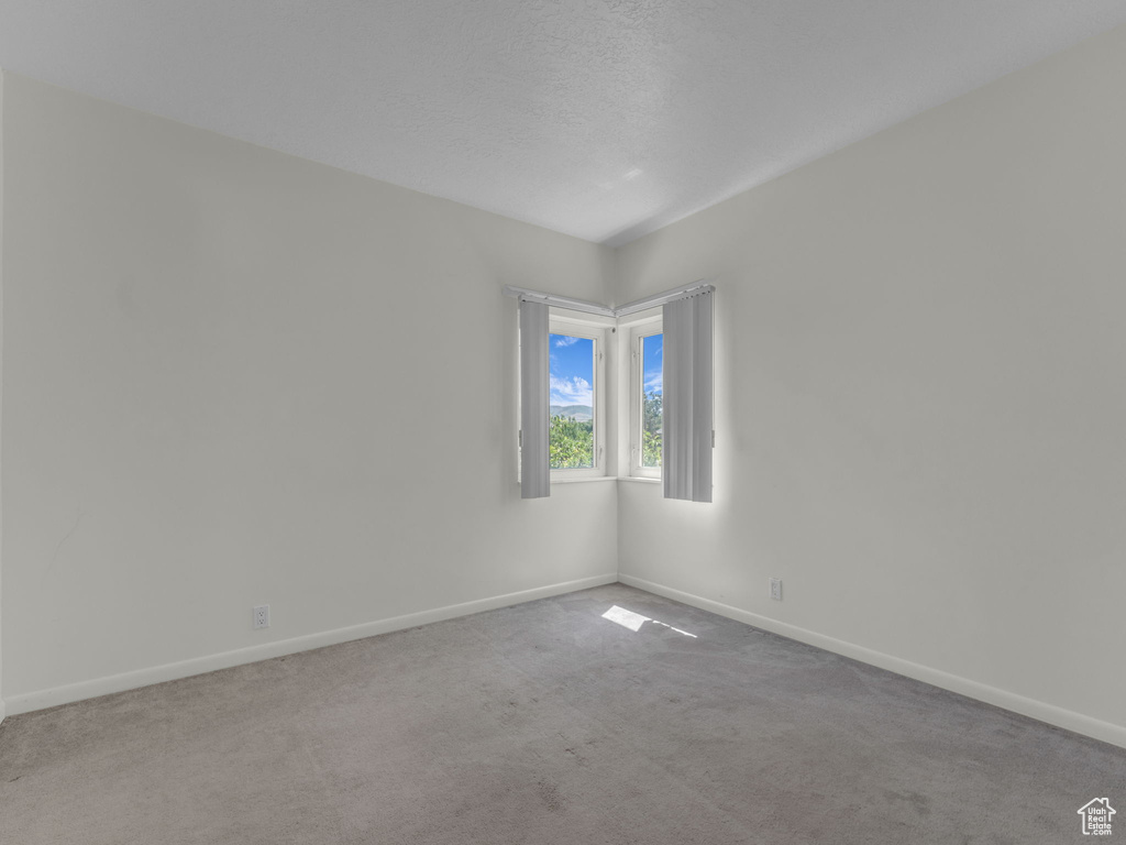 Carpeted empty room with baseboards and a textured ceiling