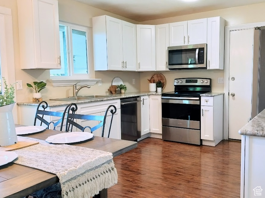 Kitchen featuring appliances with stainless steel finishes, dark wood-style flooring, plenty of natural light, and white cabinets