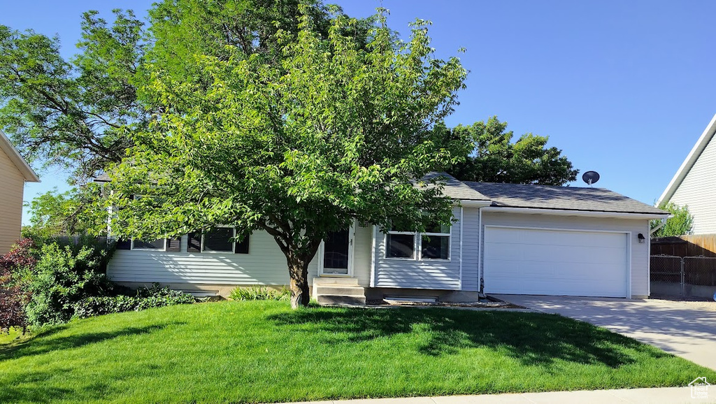 View of property hidden behind natural elements featuring entry steps, a garage, and driveway