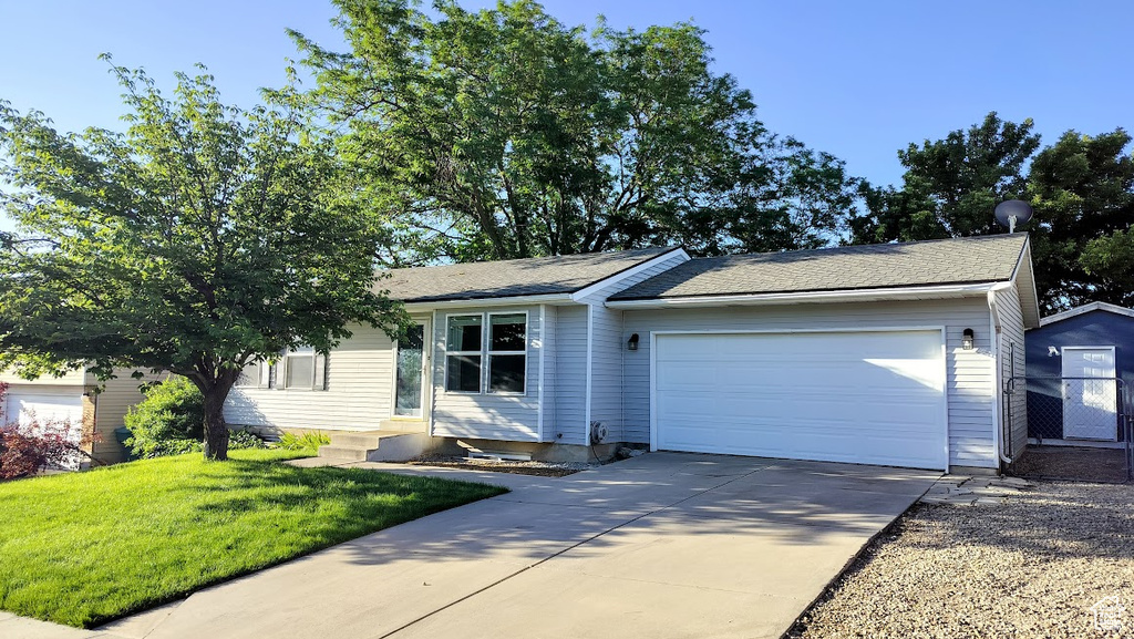 Ranch-style home featuring a garage, driveway, a front lawn, and entry steps
