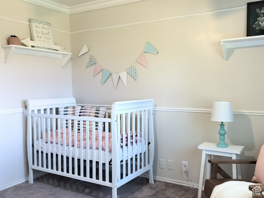 Bedroom featuring carpet flooring, crown molding, and a crib