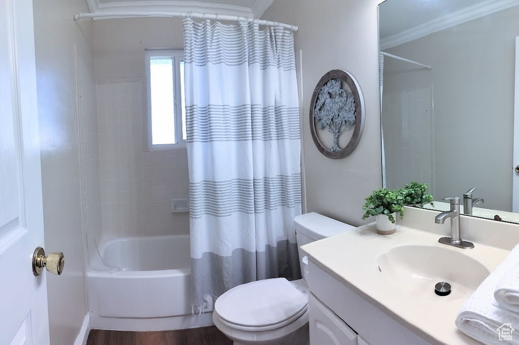 Bathroom with vanity, shower / bath combination with curtain, ornamental molding, and wood finished floors