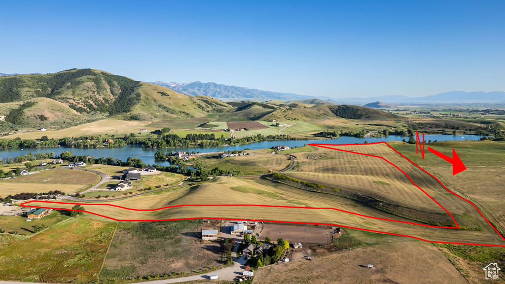 Aerial view of property and surrounding area featuring property parcel outlined and a water and mountain view