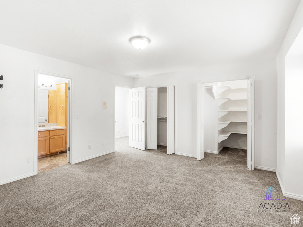 Unfurnished bedroom featuring carpet flooring, multiple closets, and ensuite bathroom